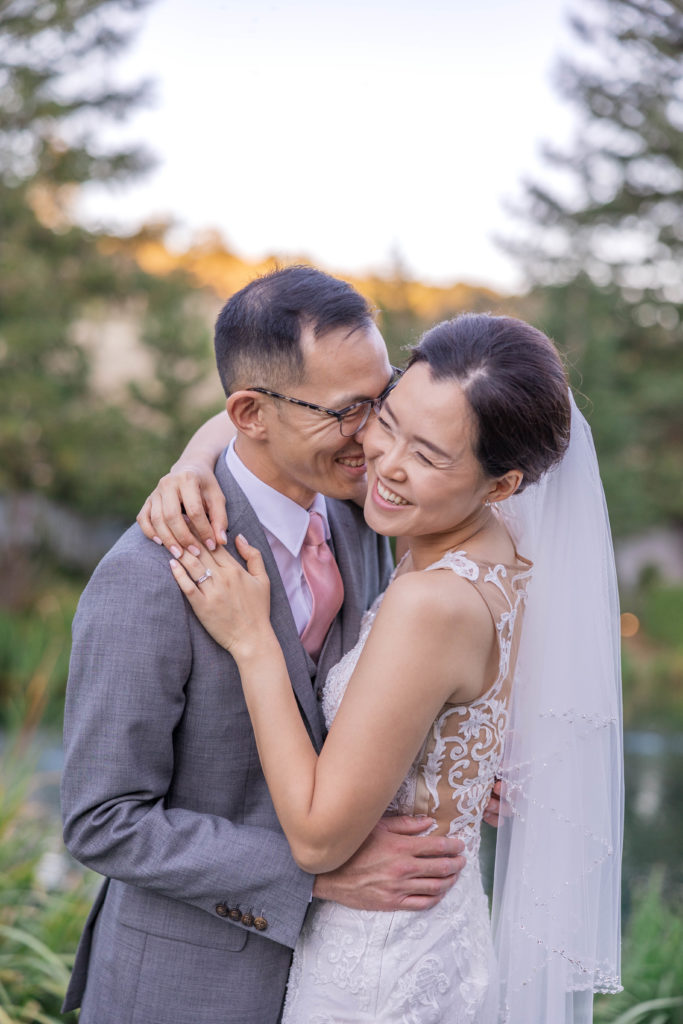 Asian couple laugh on their wedding day in a pine forest